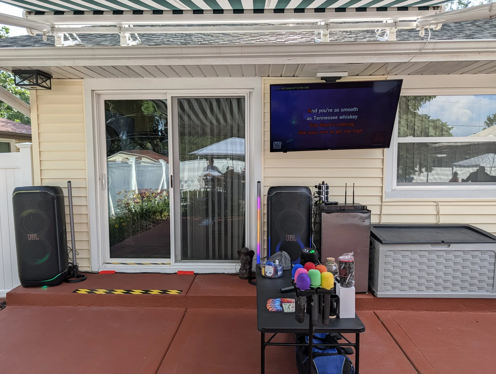 JBL speakers and light sticks beside a station of colorful wireless microphones at a covered patio party