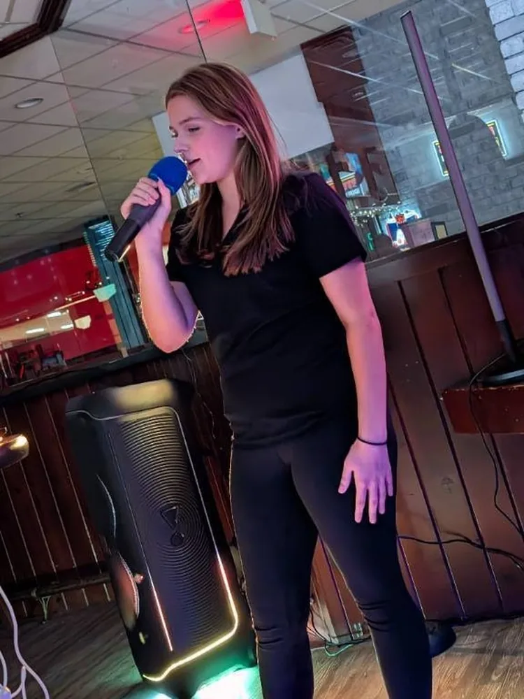 A guest singing beside Karaoke Kevin’s lighted speaker at Coach’s Corner