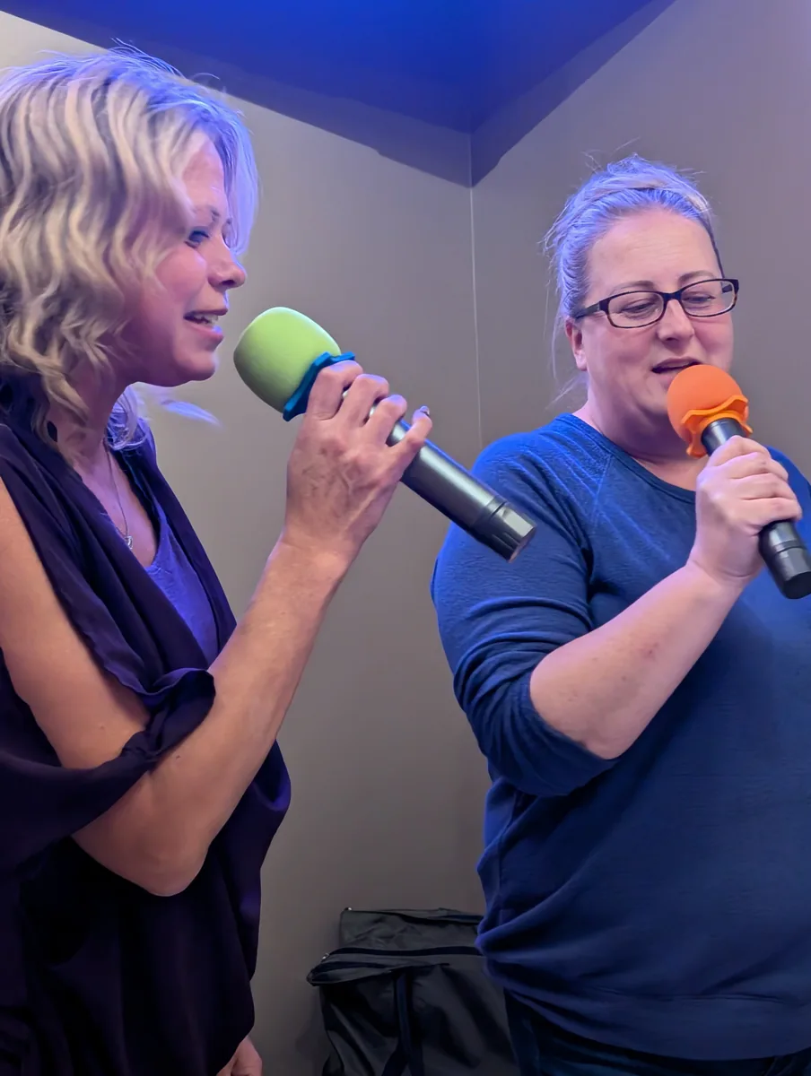 Two guests singing into colorful microphones at Jen’s Guesthouse in 2024