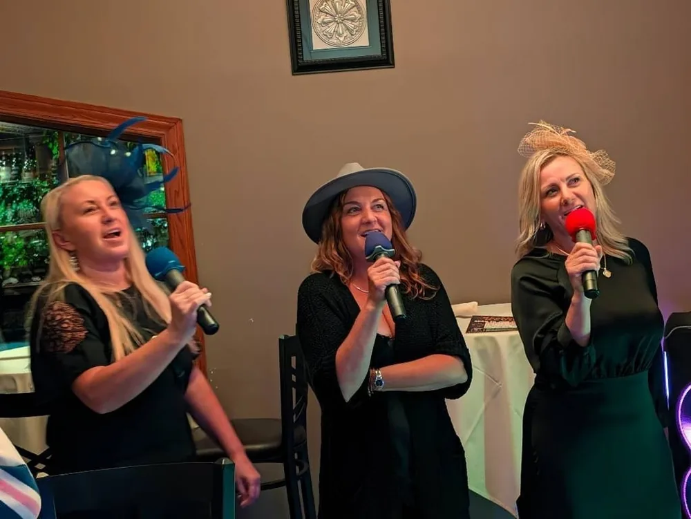 Three women singing karaoke together at Jen’s Guesthouse