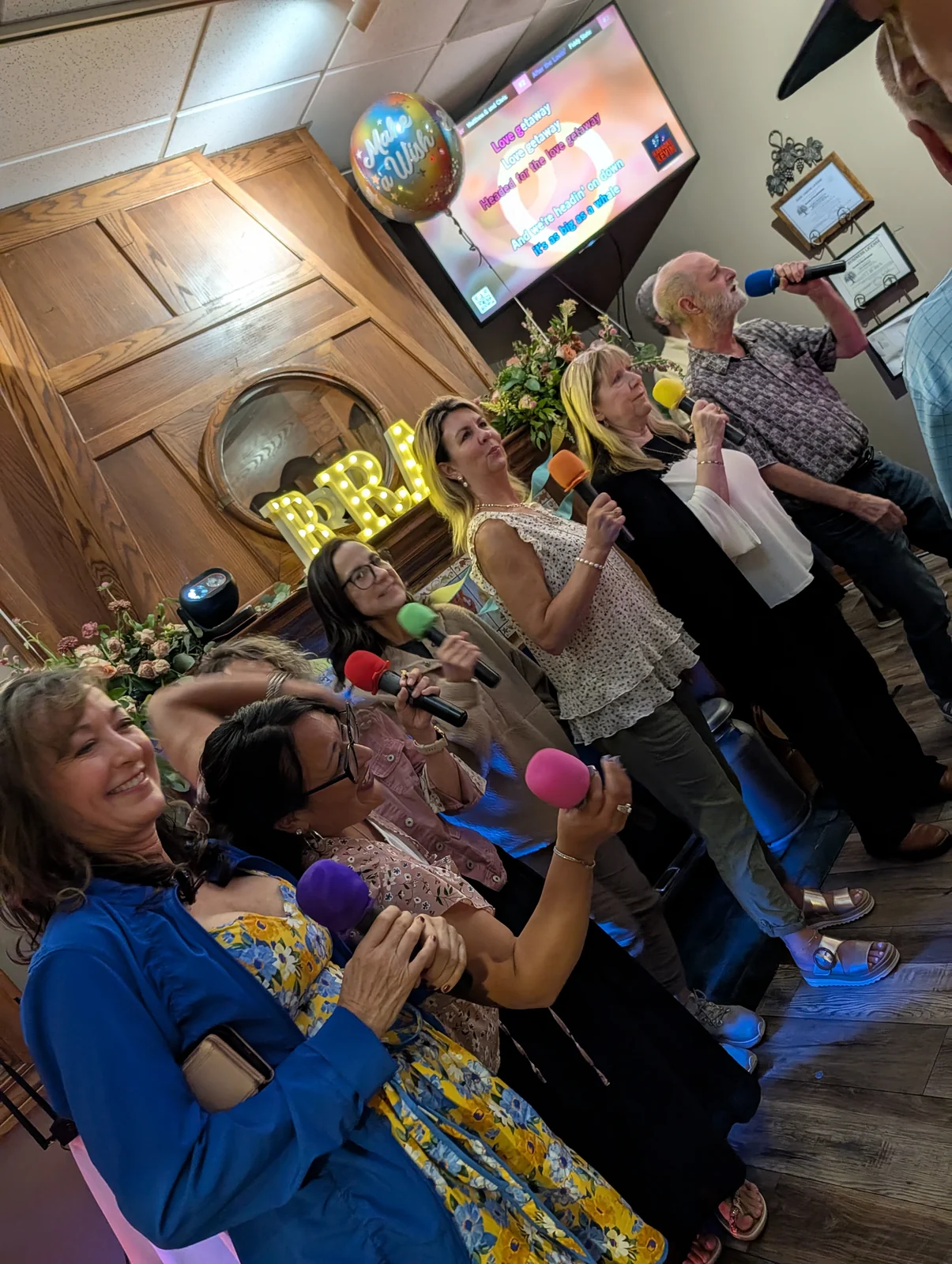 Seven guests singing together with colorful microphones at Jen’s Guesthouse